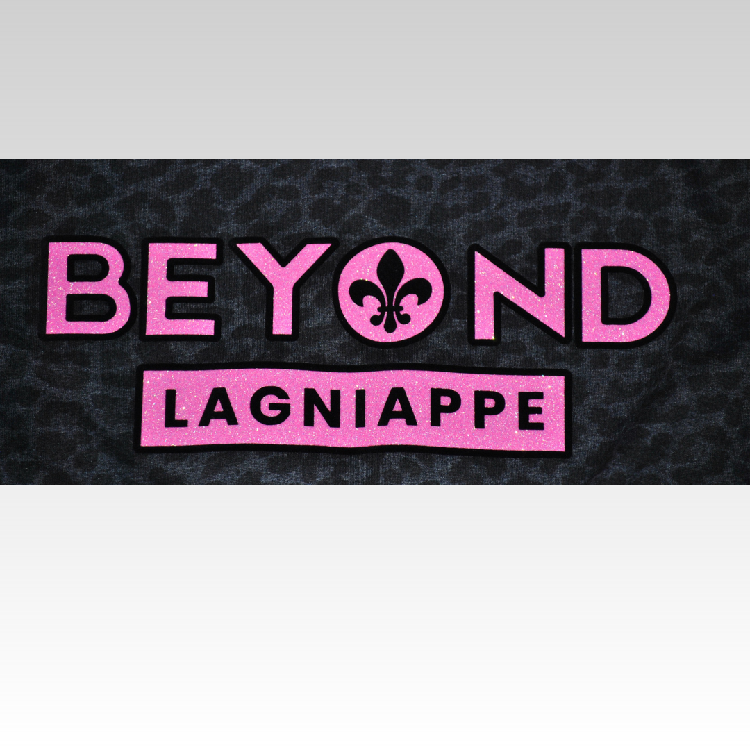 Close up of Beyond Lagniappe logo on black leopard print t-shirt.